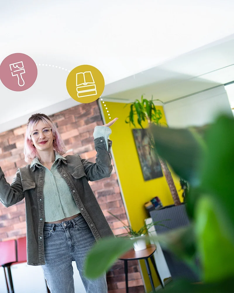 Frau reckt im Büro die Arme hoch, darüber schweben Symbole für Gestaltung und Branding