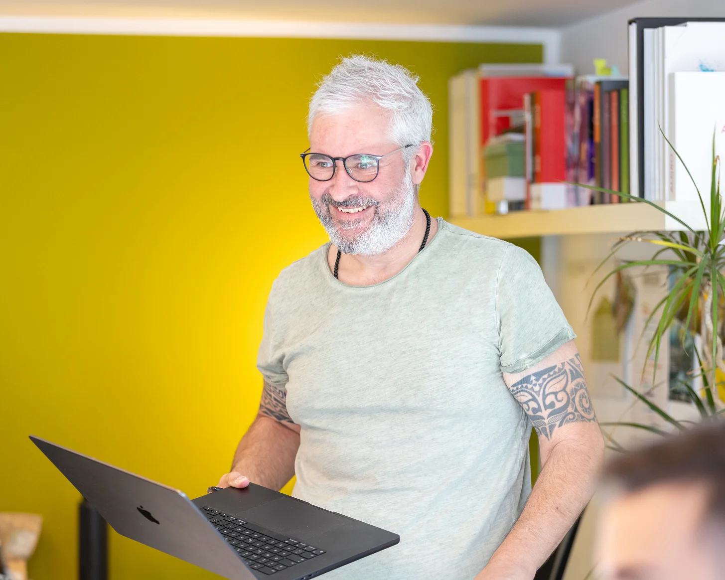 Patrick zeigt lächelnd etwas auf dem Laptop vor der grünen diffrent-Wand