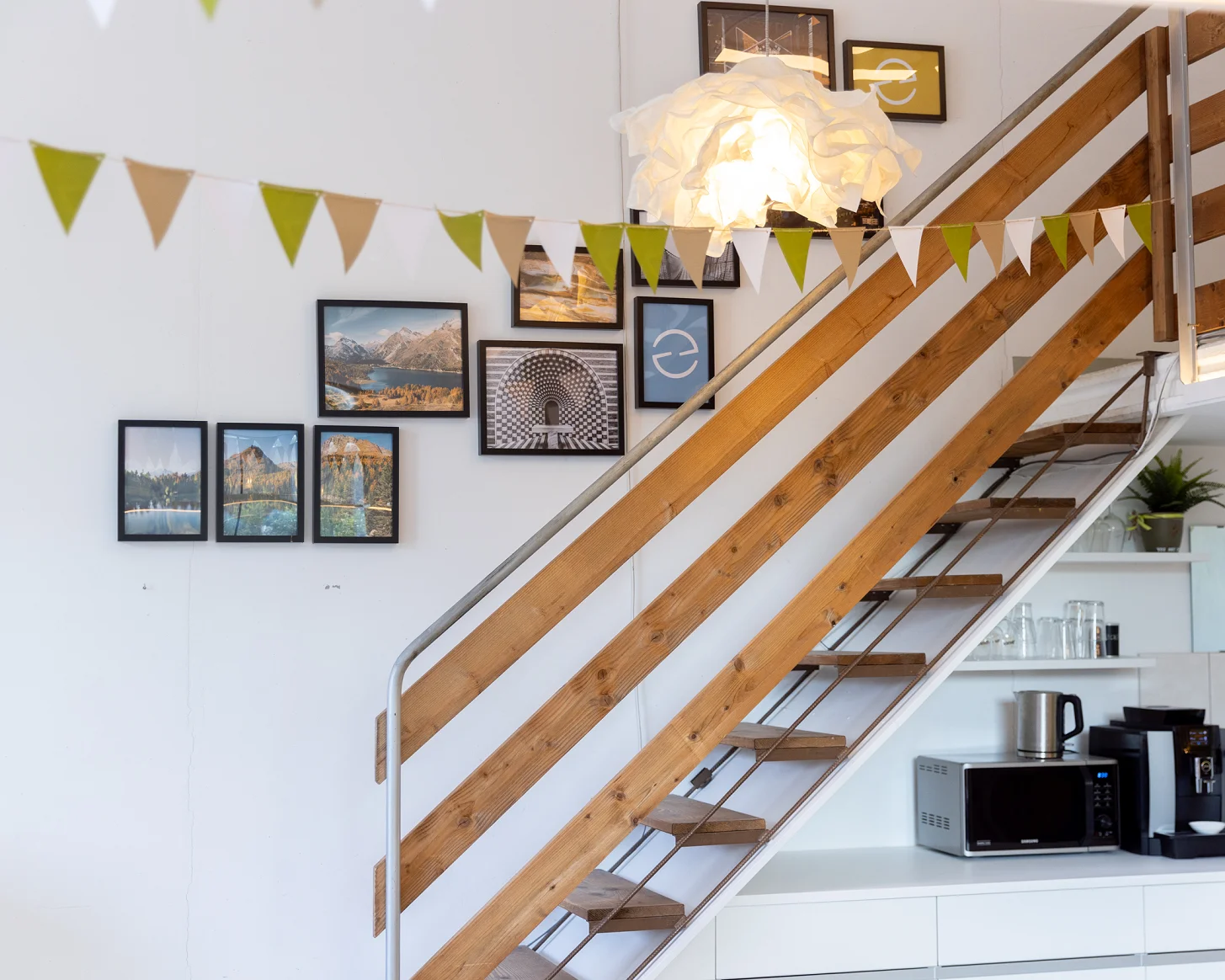 Holztreppe zur Galerie, darunter die Kaffee-Ecke, darüber eine Wimpelkette