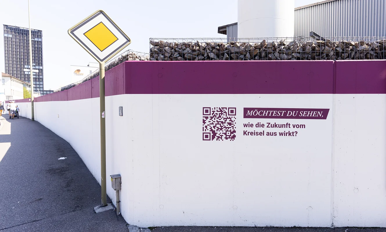 Station des Areal-Rundgangs an der Mauer: QR-Code neben der Frage «Möchtest du sehen, wie die Zukunft vom Kreisel aus wirkt?»