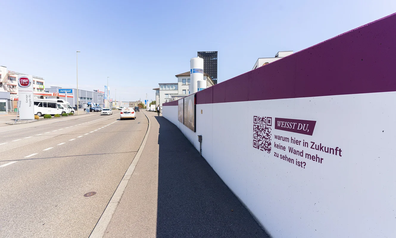 Station des Areal-Rundgangs entlang der Strasse: QR-Code neben der Frage «Weisst du, warum hier in Zukunft keine Wand mehr zu sehen ist?»