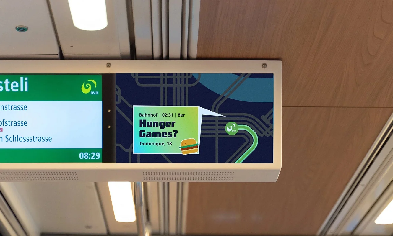 Bildschirm im Tram zeigt das Kampagnensujet «Hunger Games?» neben der Haltestellenanzeige