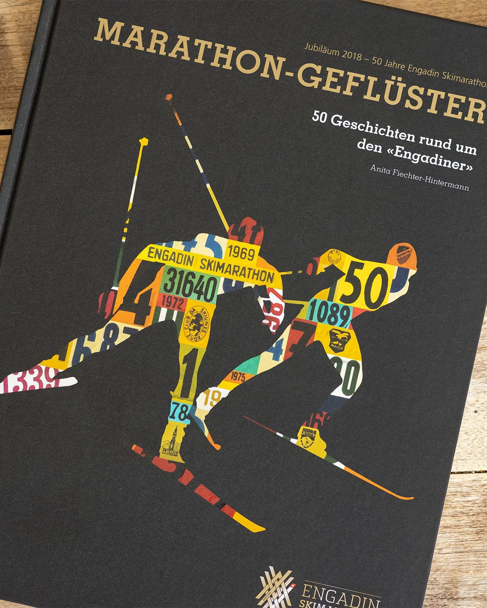 Das Jubiläumsbuch «Marathon-Geflüster» liegt geschlossen auf Holz, unten das ESM-Signet in Gold