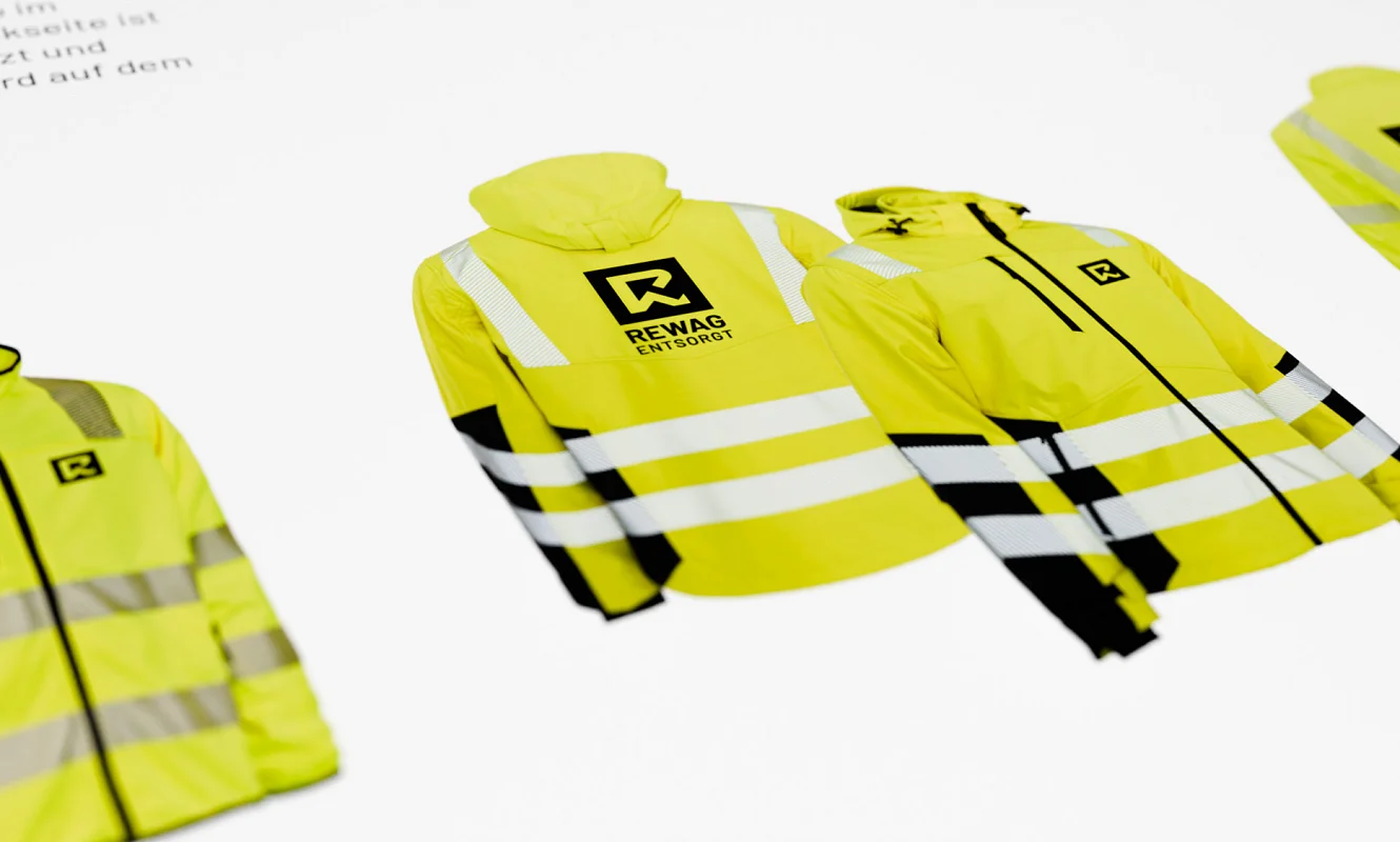 Arbeitskleidung im Manual: gelbe Warnjacken mit dem REWAG-Logo auf Brust und Rücken