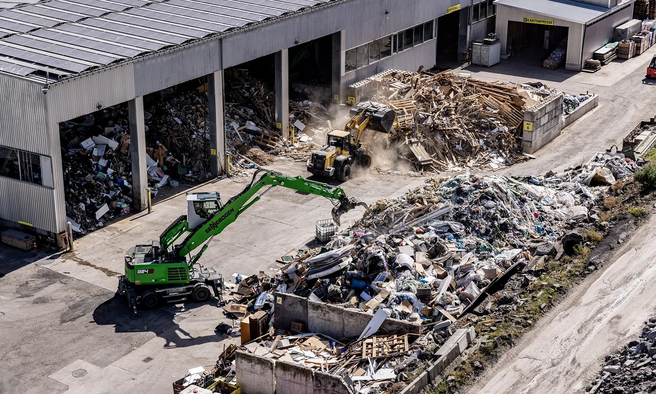 Luftbild: Radlader und Bagger arbeiten vor den offenen Boxen der Sortierhalle