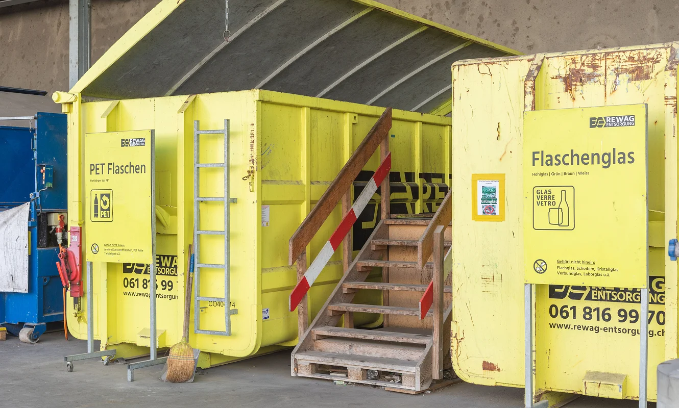 Sammelstelle mit gelben Containern und den Tafeln «PET Flaschen» und «Flaschenglas»