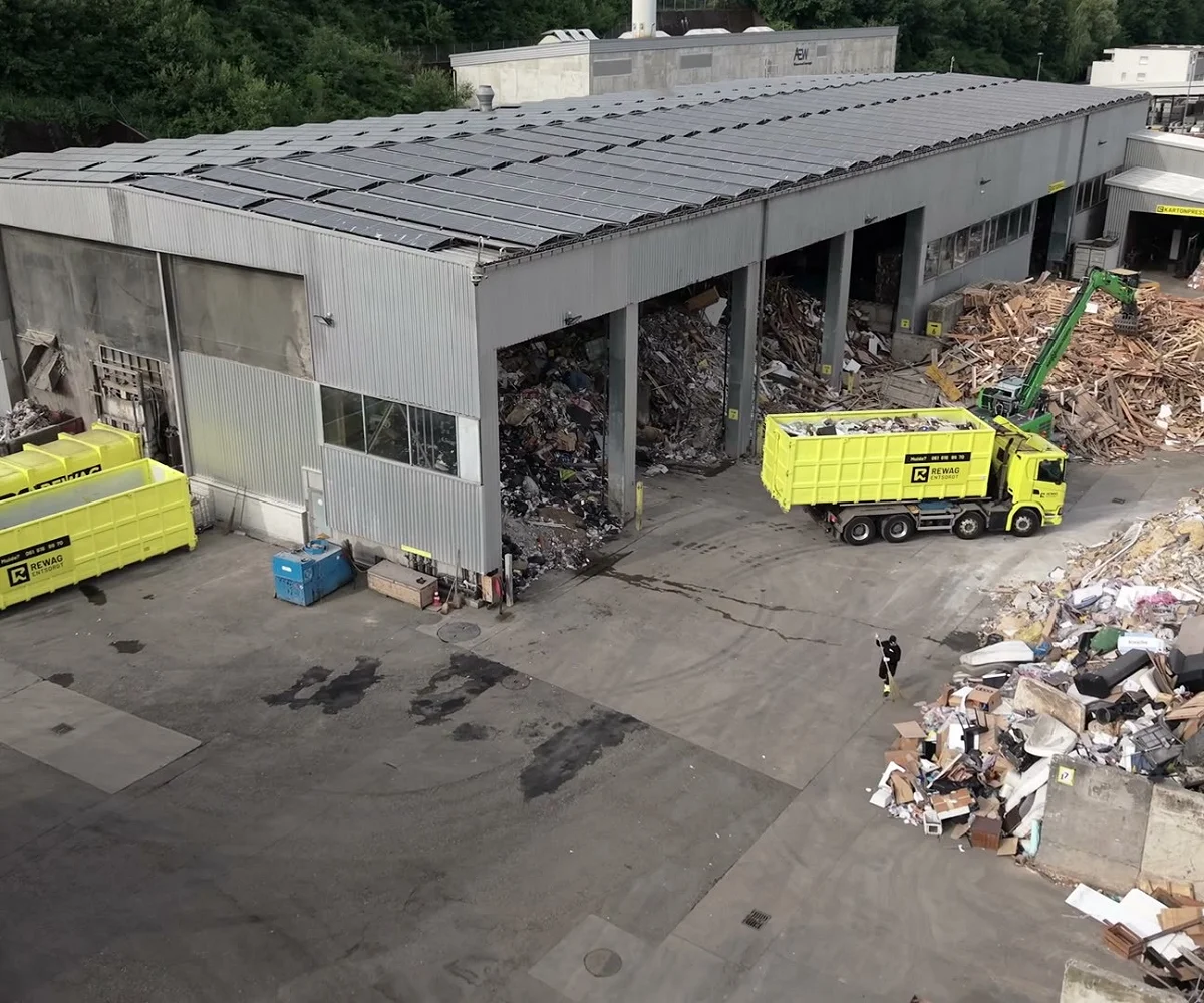 Standbild aus dem Headerfilm: Luftaufnahme des Areals mit Lastwagen und Mulden vor der Sortierhalle