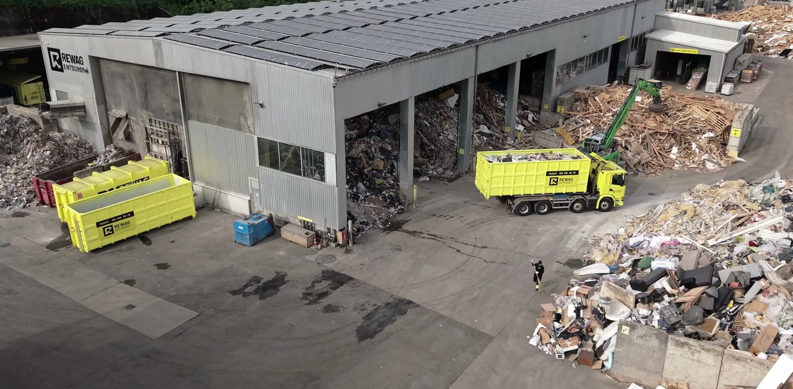 Standbild aus dem Headerfilm: Luftaufnahme des Areals mit Lastwagen und Mulden vor der Sortierhalle