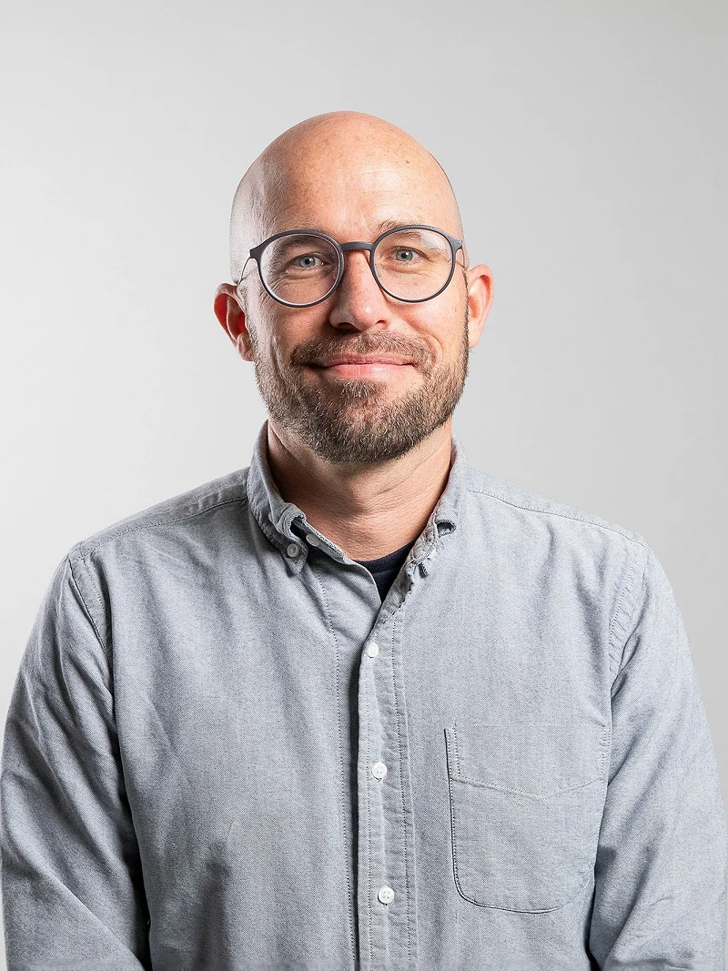 Porträt von Pascal Collaud im grauen Hemd vor hellem Hintergrund