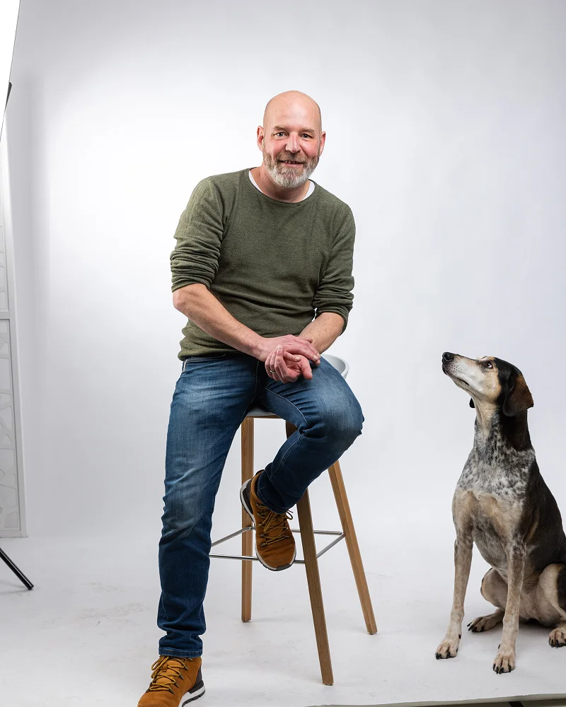 Roger auf dem Hocker im Fotostudio, daneben Inge zwischen den Studioleuchten