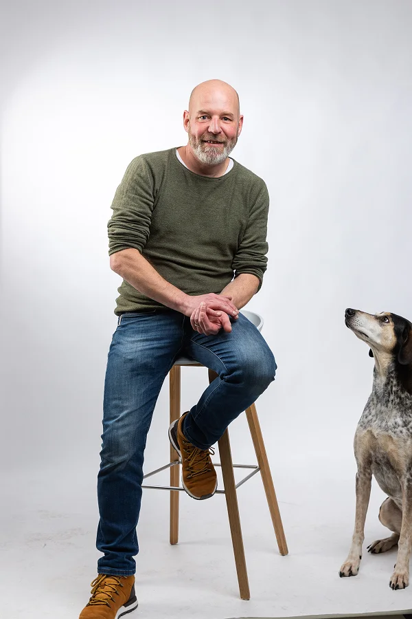 Roger auf dem Hocker im Fotostudio, daneben Inge zwischen den Studioleuchten