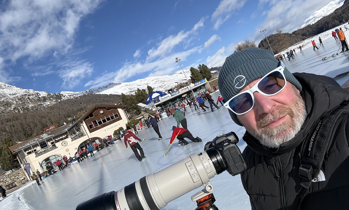 Roger mit Teleobjektiv am Rand des Eisfelds, dahinter ein Rennen auf dem gefrorenen See