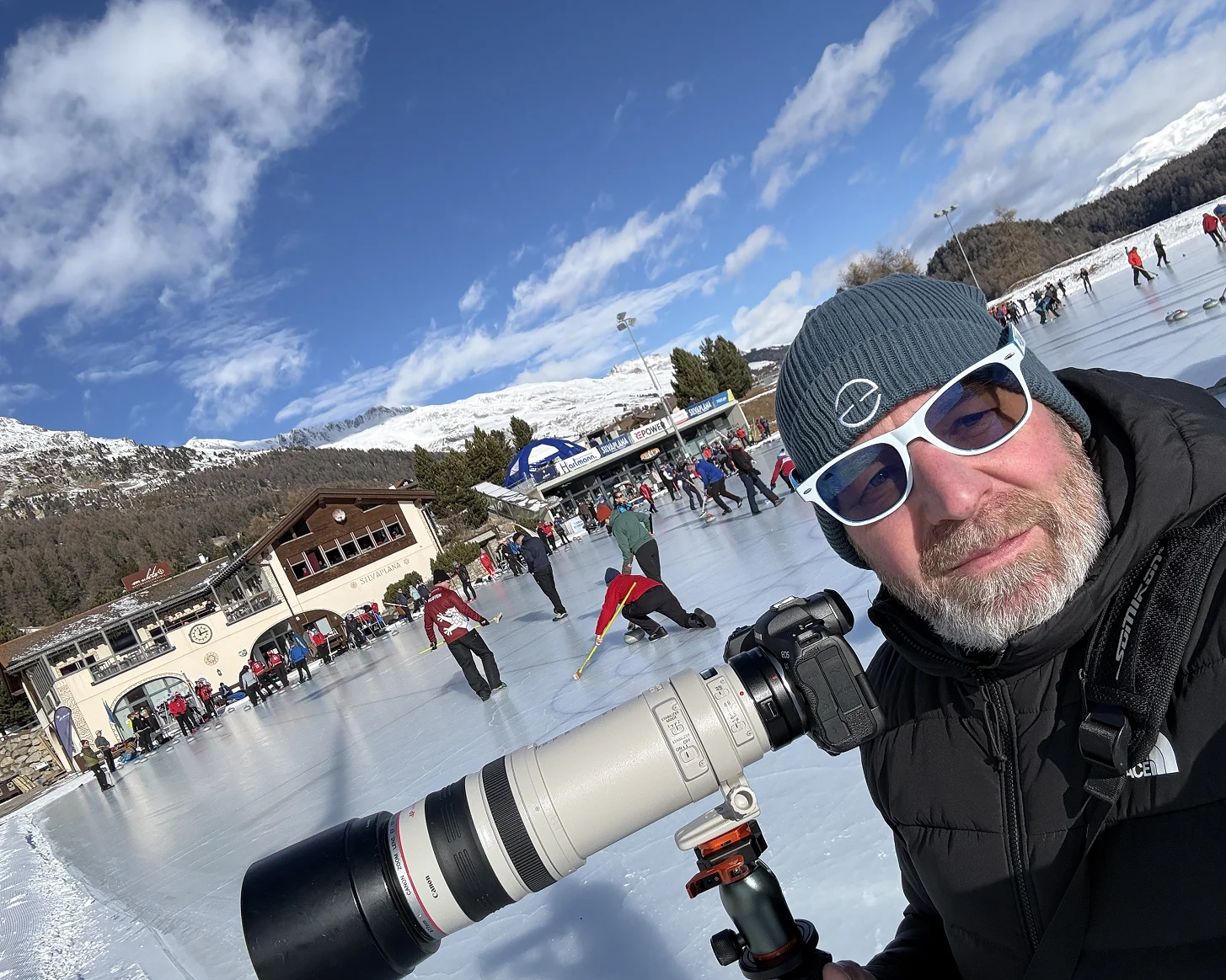 Roger mit Teleobjektiv am Rand des Eisfelds, dahinter ein Rennen auf dem gefrorenen See